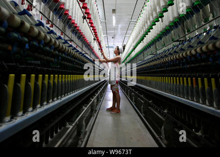 --FILE--une femme travailleur chinois s'occupe de la production de fils à destination de l'Asie du Sud-Est sur une machine à filer dans une usine de textile à Huaibei Banque D'Images