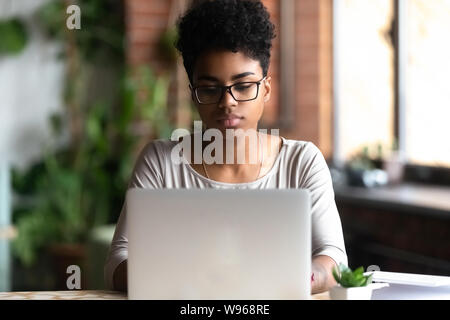 L'accent fille millénaire biracial occupé à travailler à l'ordinateur portable Banque D'Images