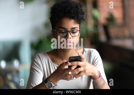 African American girl in glasses using cellphone chatting Banque D'Images