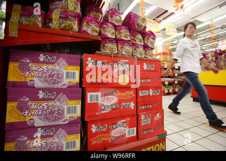 --FILE -- un membre du personnel chinois marche dernières boîtes et sacs de nouilles instantanées de Maître Kong Tingyi Holding Corp. dans un supermarché à Shanghai, Chine, Banque D'Images