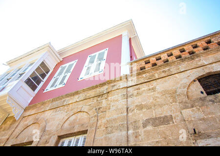 Grande maison avec des murs roses. La maison a deux grandes fenêtres et un balcon. La partie inférieure de la maison est construit de blocs de pierre. Banque D'Images