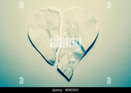Le symbole de coeur de l'ancienne, papier froissé, déchiré en deux sur un arrière-plan blanc vintage. Symbole d'un cœur brisé, l'amour malheureux. Banque D'Images