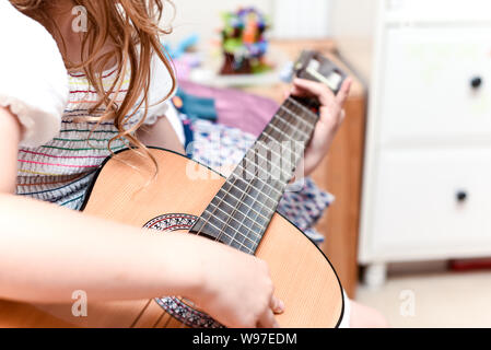 Fille apprend à jouer de la guitare pendant une leçon de musique sur l'instrument Banque D'Images