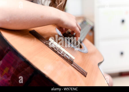 Fille apprend à jouer de la guitare pendant une leçon de musique sur l'instrument Banque D'Images