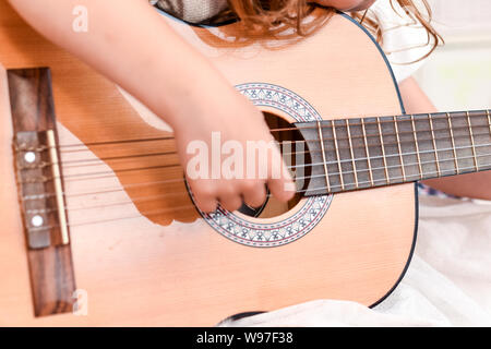 Fille apprend à jouer de la guitare pendant une leçon de musique sur l'instrument Banque D'Images