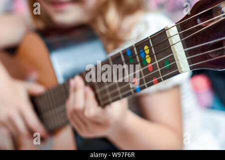 Fille apprend à jouer de la guitare pendant une leçon de musique sur l'instrument Banque D'Images