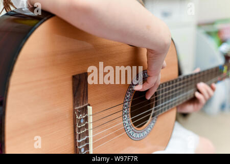 Fille apprend à jouer de la guitare pendant une leçon de musique sur l'instrument Banque D'Images