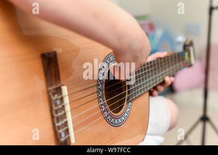 Fille apprend à jouer de la guitare pendant une leçon de musique sur l'instrument Banque D'Images