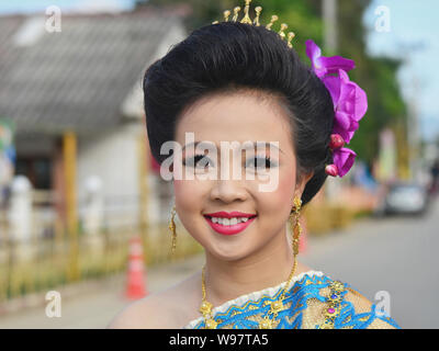 S'habille jolie fille thaïe avec des fleurs dans ses cheveux prend part dans le village historique de la street parade Lanna et sourit pour la photo. Banque D'Images