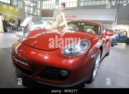 --FILE--un modèle pose à côté d'une Porsche Cayman lors d'une auto show dans la ville de Hangzhou, province de Zhejiang, Chine de l'est le 13 octobre 2010. Un luxe allemand Banque D'Images