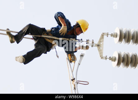 Une mise à niveau des lignes de transport d'électricité électricien chinois dans la ville de Huaibei, à l'est la province de l'Anhui, Chine 17 mai 2011. Une vague de pannes de matériel roulant qui a commencé ea Banque D'Images