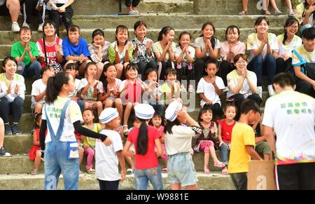 (190812) -- RONGSHUI, Août 12, 2019 (Xinhua) -- Des bénévoles de Macao et les enfants de regarder les performances à une classe par intérim à Wuying, un village de l'ethnie Miao dans le cadre d'une administration conjointe par Rongshui County dans la région autonome Zhuang du Guangxi et ses voisins Congjiang Comté de la province du Guizhou, au sud-ouest de la Chine, 10 août 2019. Plus de 30 étudiants bénévoles de la Chine du sud Macao offre un service d'enseignement d'une semaine pour les enfants dans ce village éloigné. Les bénévoles préparé différentes classes dont la peinture, d'agir, de la science et de PE pour enrichir les vacances d'été pour enfants local et br Banque D'Images