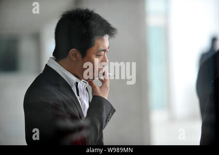 --FILE--un Chinois fume dans la rue à Shenyang city, Liaoning Province nord-est de Chines, 26 février 2011. Les fabricants de cigarettes sont tricher Banque D'Images