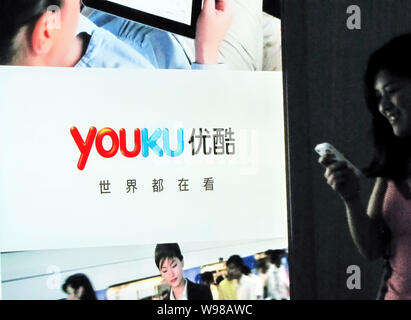 --FILE--Une femme chinoise utilise son téléphone mobile devant une publicité pour le site de partage de vidéo en ligne Youku.com à Shanghai, Chine, 29 juin 2011. Banque D'Images