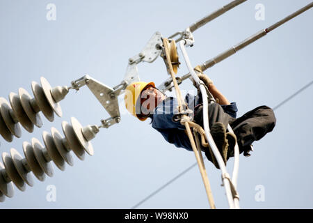 Une mise à niveau des lignes de transport d'électricité électricien chinois dans la ville de Huaibei, à l'est la province de l'Anhui, Chine 17 mai 2011. Une vague de pannes de matériel roulant qui a commencé ea Banque D'Images