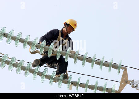 Une mise à niveau des lignes de transport d'électricité électricien chinois dans la ville de Huaibei, à l'est la province de l'Anhui, Chine 17 mai 2011. Une vague de pannes de matériel roulant qui a commencé ea Banque D'Images
