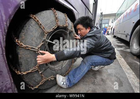 Un pilote chinois met les chaînes sur les pneus d'un bus pour éviter de glisser sur l'autoroute congelé après la pluie glacée, au sud-ouest de la ville de Guiyang Chines G Banque D'Images