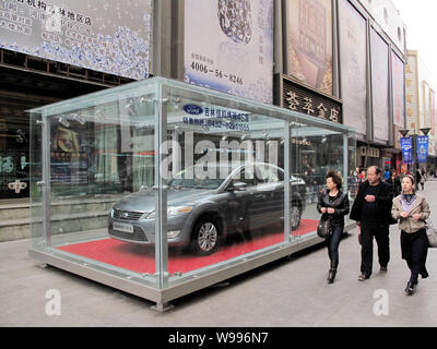 --FILE--Local des résidents chinois regarder une Ford Mondeo vedette sur une rue commerçante de la ville de Jilin, province de Jilin, en Chine du nord-est 6 avril 2011. C Banque D'Images