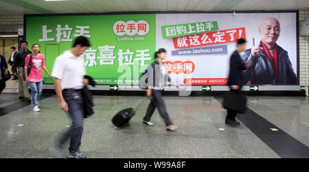 --FILE--résidents locaux à pied passé une publicité en ligne pour l'achat de groupe lashou.com site avec le portrait de l'acteur chinois Ge Vous à Beijing, Chine Banque D'Images