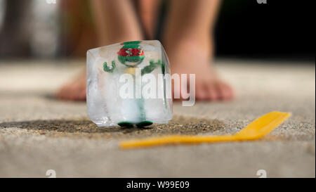 Ninja Turtle pris dans la glace cube, la fusion dans le soleil en face d'enfants pieds Banque D'Images