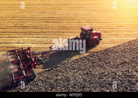 Machine agricole la récolte dans les champs. Le tracteur tire sur un mécanisme pour la fenaison. La récolte en automne le matin à l'aube dans l'agroalimentaire. Banque D'Images