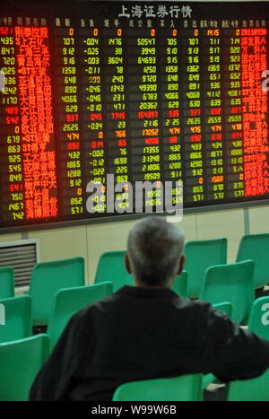 Un investisseur chinois se penche sur le prix des actions (vert pour la baisse des prix) à une maison de courtage à Dalian, au nord-est de la province de Liaoning, Chine 30 septem Banque D'Images