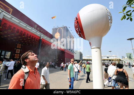 Un visiteur étranger se trouve en face d'un pulvérisateur de refroidissement pour refroidir lui-même vers le bas dans le site de l'Expo de Shanghai, Chine, le 2 mai 2010. Plus de 433 000 peop Banque D'Images