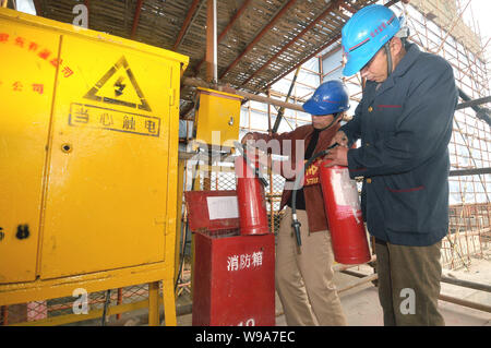 Les travailleurs chinois vérifier les extincteurs et autres équipements de protection incendie sur un chantier de construction au cours d'une inspection de sécurité-incendie à Shanghai, Banque D'Images