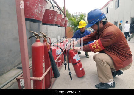 Les travailleurs chinois vérifier les extincteurs et autres équipements de protection incendie sur un chantier de construction au cours d'une inspection de sécurité-incendie à Shanghai, Banque D'Images