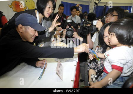 Acteur kungfu chinois Jet Li présente une carte avec sa signature à un enfant au cours d'une activité de bienfaisance afin de sensibiliser spéciale pour le séisme de Yushu touchés dans northwe Comté Banque D'Images