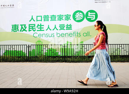 --FILE--un résident chinois locaux passe devant un panneau de propagande pour le sixième recensement national de la population de Beijing, Chine, 12 août 2010. Chine Banque D'Images