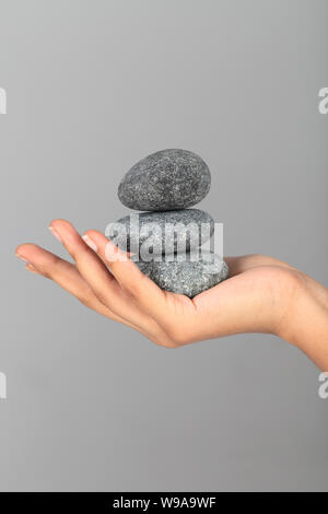 Close up of a person&#39;s hand holding pile of stones Stock Photo