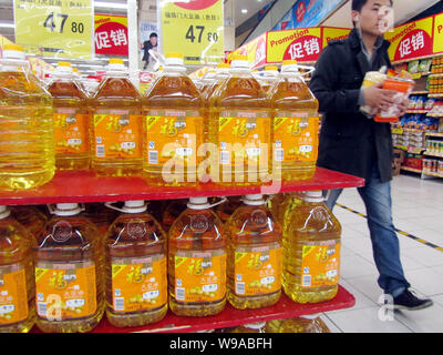 --FILE--un client chinois marche dernières bouteilles d'huile de cuisson dans un supermarché à Shanghai, Chine, 18 novembre 2010. Le prix imposé par le gouvernement est le th Banque D'Images