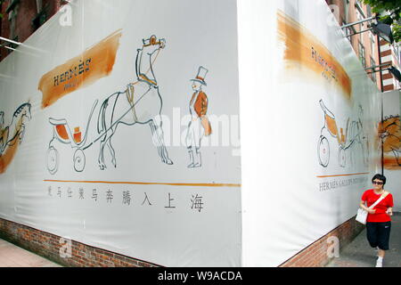 Une femme chinoise passe devant une publicité pour Hermes Hermes à l'extérieur de l'hôtel particulier dans le quartier de Luwan à Shanghai, Chine, le 9 août 2010. De luxe français Banque D'Images