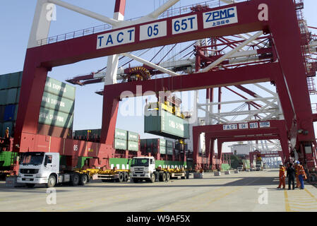 --FILE--grues, camions de charge avec la Chine des conteneurs déchargés d'un navire porte-conteneurs à un terminal à conteneurs du port de Tianjin, Chine, 1 Apri Banque D'Images