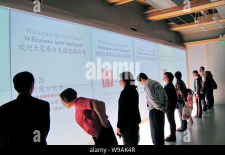 Les visiteurs posent devant un écran à participer à la ville à la maison de jeu sino-allemande dans le site de l'Expo de Shanghai, Chine, le 11 mai 2010. Ge Banque D'Images