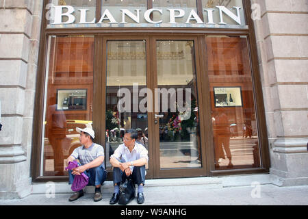 Les touristes prendre le reste en face d'une boutique Blancpain à la Swatch Art Peace Hotel sur le Bund à Shanghai, Chine, le 27 mai 2010. Swiss watch giant sw Banque D'Images