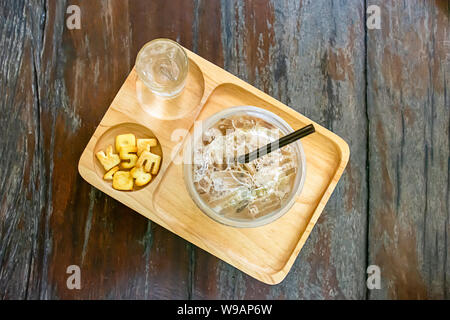 Verre de café espresso froid , l'eau et du pain qui a plus de numéros et Ze dans le plateau en bois sur la table. Banque D'Images