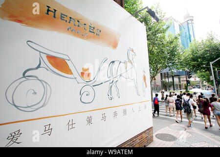 Les résidents locaux chinois passe devant une publicité pour Hermes Hermes à l'extérieur de l'hôtel particulier dans le quartier de Luwan à Shanghai, Chine, le 9 août 2010. Le Français Banque D'Images