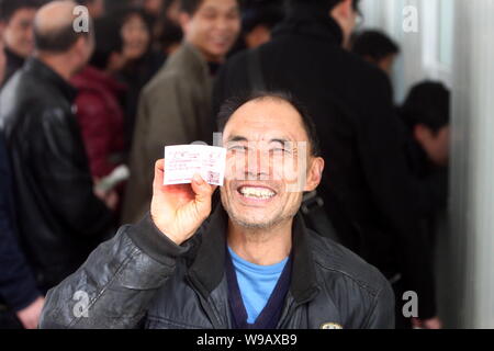 Un travailleur migrant chinois montre son billet de train devant des foules de passagers la queue pour acheter des billets à un ticket sales center de la Shanghai Ra Banque D'Images