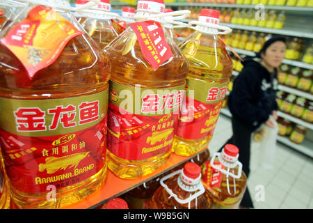 --FILE--un client chinois marche dernières bouteilles d'arawana l'huile de cuisson dans un supermarché dans la ville de Nantong, Chine de l'est de la province de Jiangsu, le 11 novembre 2010. Banque D'Images