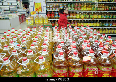 --FILE--un client chinois marche dernières bouteilles d'arawana l'huile de cuisson dans un supermarché dans la ville de Nantong, Chine de l'est de la province de Jiangsu, le 24 novembre 2010. Banque D'Images