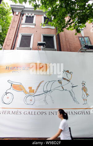 Une femme chinoise passe devant une publicité pour Hermes Hermes à l'extérieur de l'hôtel particulier dans le quartier de Luwan à Shanghai, Chine, le 9 août 2010. De luxe français Banque D'Images