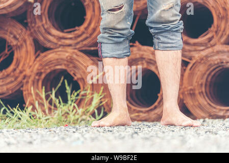 L'homme marche pieds nus sur le site de construction. Banque D'Images