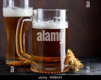 Une chope de bière et un verre de bière sur un fond sombre . Le blé de la bière allemande. Oktoberfest. marron foncé fond Copyspace Banque D'Images