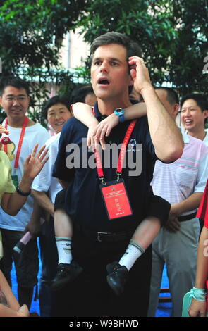 Timothy Shriver, président-directeur général de Special Olympics International, porte un garçon chinois sur le dos tout en parlant à la population locale après les jeunes Banque D'Images