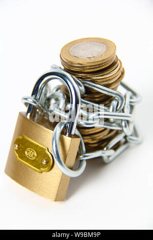 Stack of coins wrapped of a chain with a padlock Stock Photo