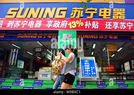 --FILE--deux jeunes femmes chinoises devant une chaîne de magasins d'appareils ménagers Suning à Chongqing, Chine, le 19 avril 2009. Détaillant de produits électroniques chinois Banque D'Images