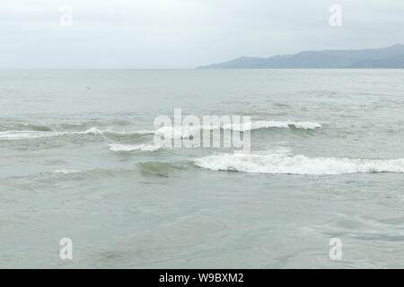 Des bouffées d'eau de mer. Vagues à proximité de la mer. Ciel nuageux sombre au-dessus de la mer. L'eau pulvérisée sur la rive. Ciel gris sur la baie. Banque D'Images