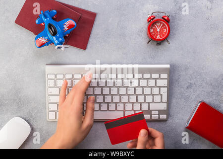 Avion avec près de passeports de payer par carte de crédit et le clavier. Réservation de billets en ligne concept. Un gain de temps. Horloge rouge, fond gris. Banque D'Images